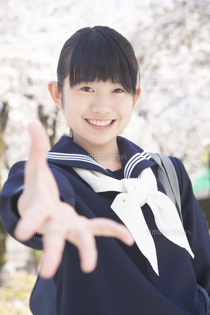 白い背景の前で両手を前に出している白いタンクトップ姿の笑顔の若い女性の写真素材17782994- PIXTA